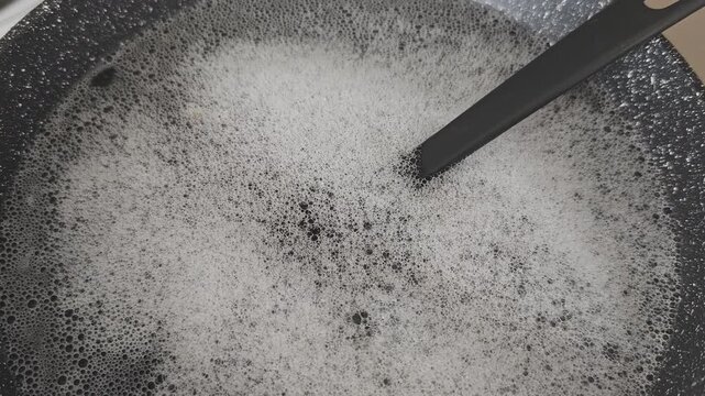 Dishwashing detergent foam fills a large bowl in a kitchen during a cleaning session