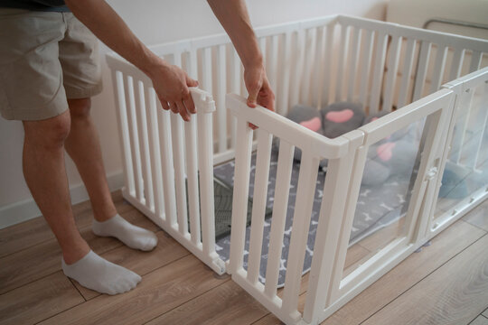 A person is setting up a dog enclosure in a home. They adjust the door latch and prepare the space for the pet