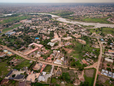 Aerial view of the town of Kakuri, featuring residential buildings, roads, and a river flowing through the landscape in Kakuri, Kaduna, Nigeria.