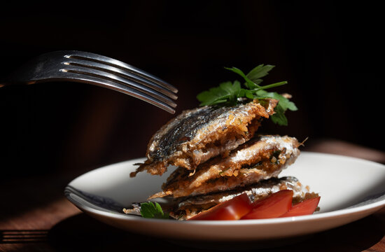 Close-up of freshly prepared sarde a beccafico. A traditional Sicilian fish dish featuring stuffed sardines. A fork is reaching for the food.