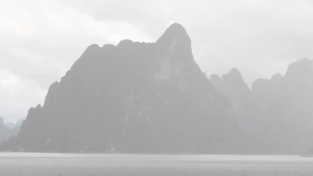 Ratchaprapha Dam on a rainy day at khao sok national park, surat thani province thailand featuring spectacular limestone mountains shrouded in mist.