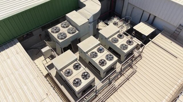 Aerial drone view of industrial HVAC systems, air conditioning units, ventilation fans, and piping on the rooftop