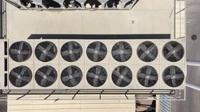 Aerial drone view of industrial HVAC systems, air conditioning units, ventilation fans, and piping on the rooftop
