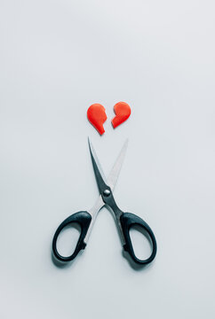 Scissors cutting a broken heart symbol isolated on a white background. Separation and heartbreak represent concepts of divorce, breakup, emotional pain, and ending relationships.