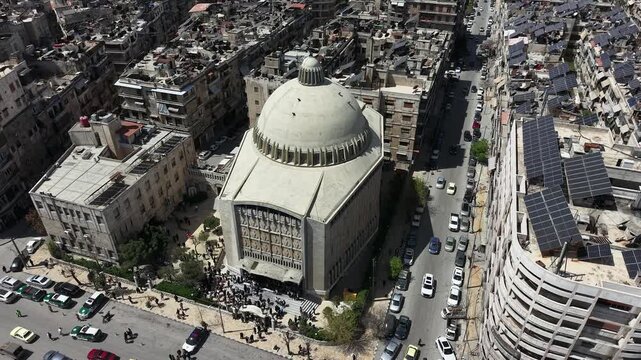 Aerial drone view of a church and Christian worshipers gathering in Syria. Weekly prayers and religious minorities in the Middle East. Golden dome and religious architecture.