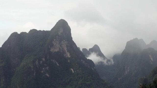 Ratchaprapha Dam on a rainy day at khao sok national park, surat thani province thailand featuring spectacular limestone mountains shrouded in mist.