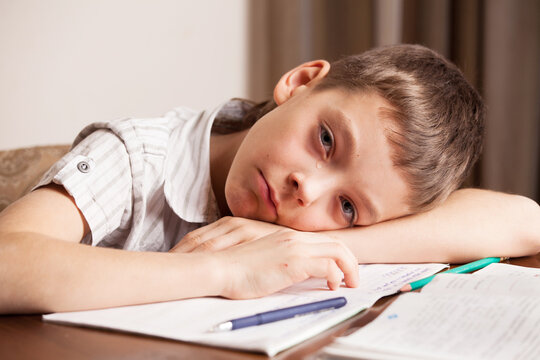 Sad boy crying over homework at a table. Childhood stress, learning difficulty and emotional exhaustion during home study. Education, mental health and family support concept.