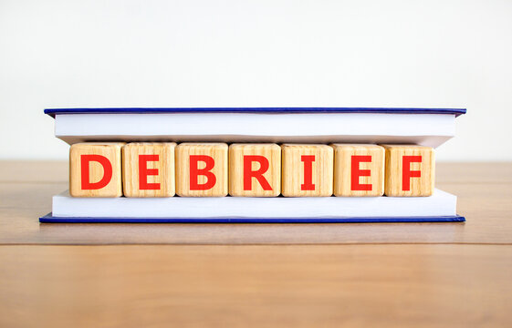 Debrief word symbol. Concept word Debrief on beautiful wooden blocks in book. Beautiful wooden table white background. Business debrief word concept. Copy space.