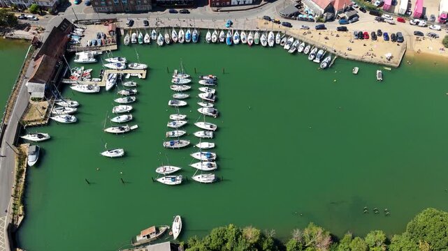 Aerial view of sailing yachts moored in Eling Creek beside a busy shipping terminal with stacked cargo containers in Southampton, Hampshire, UK