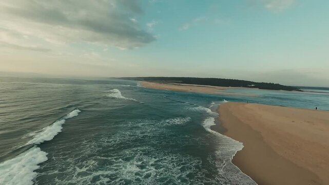 Golden waves crash on wide, sandy shores. Two tiny figures walk along the quiet beach. Overcast sky casts soft, warm light. Eyes gaze at calm, endless horizon