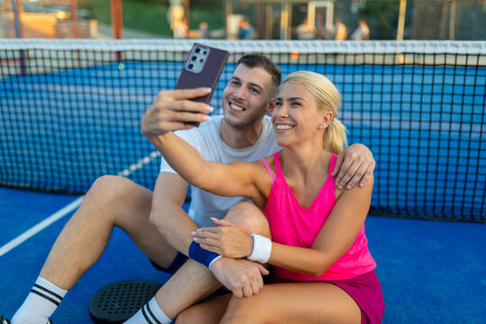 Happy couple taking selfie on padel court