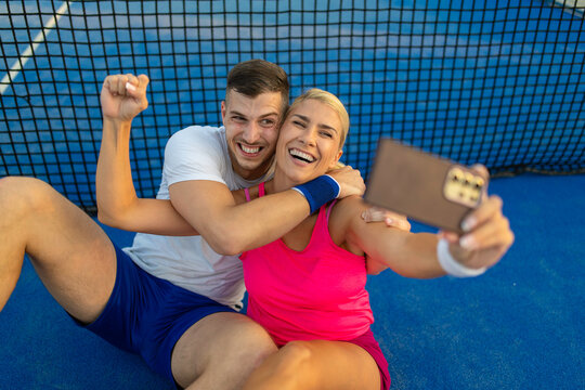 Happy couple taking selfie after winning tennis match
