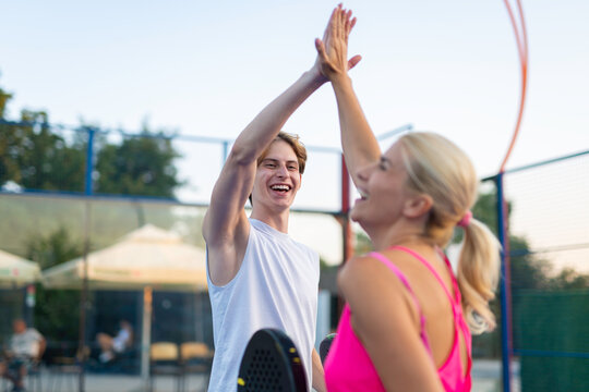 Padel tennis players celebrating victory with a high five