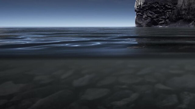 Waves touch the rocky shore as the sun sets. The sky appears dark while the ocean reflects the fading light. The scene captures natures beauty in a simple moment.