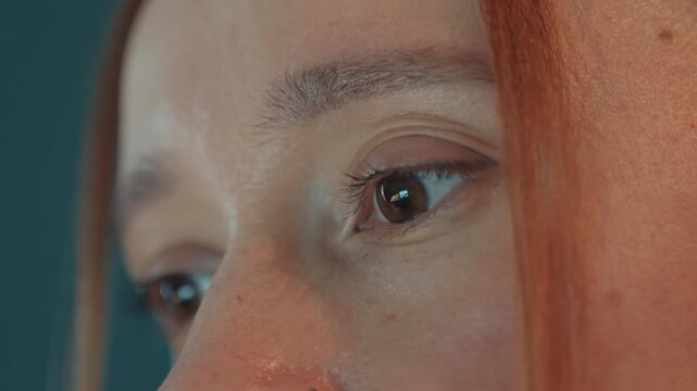 Close up of woman face focusing on eyes and skin texture. Teal background suggests indoor setting consistent lighting conditions. Subtle changes in angle capture details