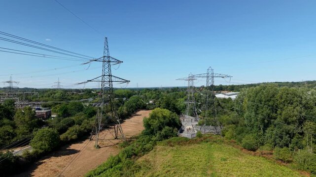 Aerial View of High Voltage Power Lines and Lattice Pylons Across Rural Landscape in the UK