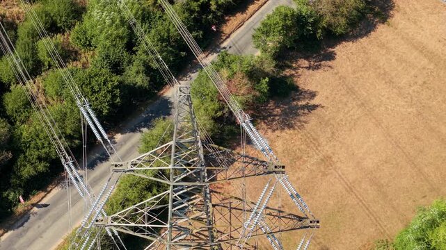 Aerial View of High Voltage Power Lines and Lattice Pylons Across Rural Landscape in the UK