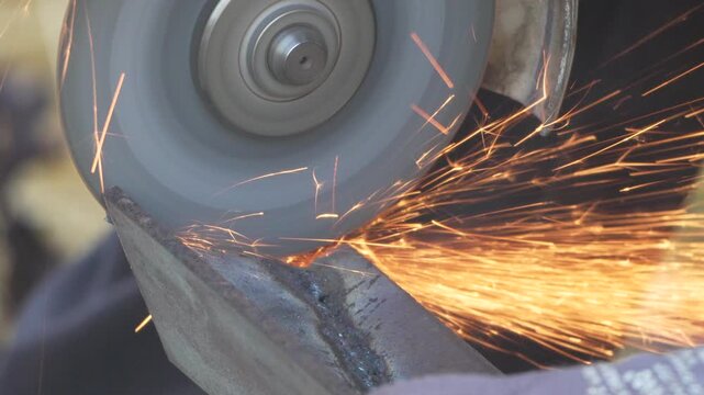 Bright orange sparks shower during manual metal grinding at a shop, showing craftsmanship in progress. Static close-up shot capturing abrasive contact.