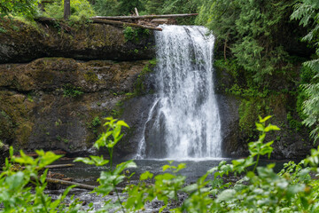 Obraz premium Water flows over rocks in a forested area during the afternoon