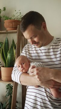 Young, loving father carefully holding his newborn son, gently stroking him and kissing his head. Heartwarming moment showcasing the deep connection and tenderness within a new family