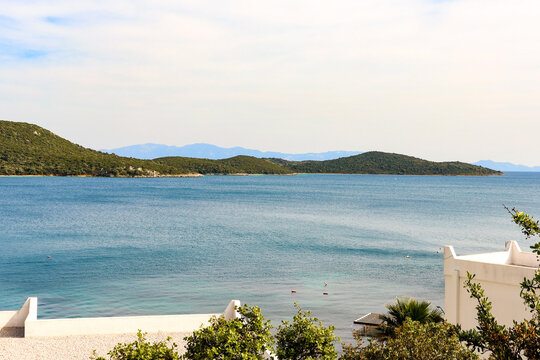 Coastal landscape featuring lush green islands, serene blue water of the mediterranean sea, and white resort buildings