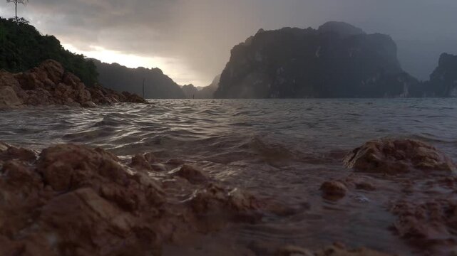 Ratchaprapha Dam in the morning featuring sunlight and mist amidst khao sok national park in surat thani province thailand where towering limestone cliffs rise from the freshwater reservoir.