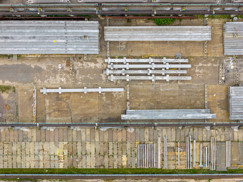 Aerial view of a prestressed concrete elements production yard with rows of stacked beams, construction materials, and industrial ground surfaces in Poland.