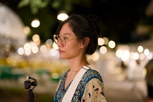 Portrait of a young woman at a night market with bokeh lights