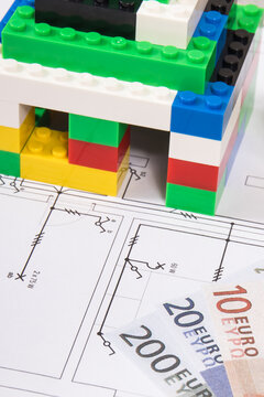 Small house made of toy blocks, housing plan with electric installation and euro banknotes. Building or renting home