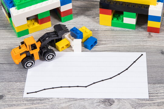 Houses made of toy blocks and rising graph representing increase in prices of building or purchasing home