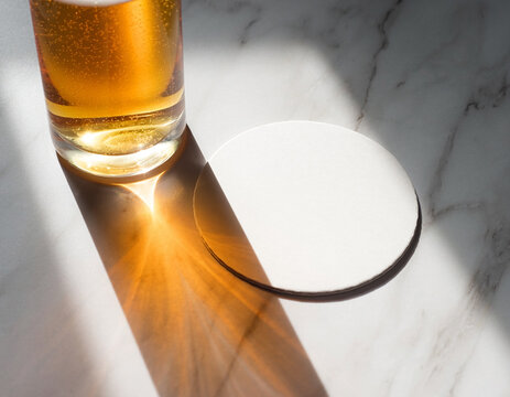 Round white drink coaster mockup template beside beer glass on marble