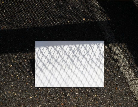 Blank white flyer mockup template on asphalt with mesh shadow