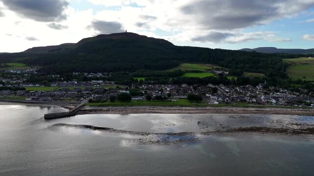 Aerial drone footage of Golspie town, coastal shoreline, and Ben Bhraggie hill with the Duke of Sutherland Monument, Scottish Highlands, UK