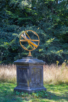 Golden armillary sundial on stone plinth at Castle Duivenvoorde gardens in Voorschoten, the Netherlands