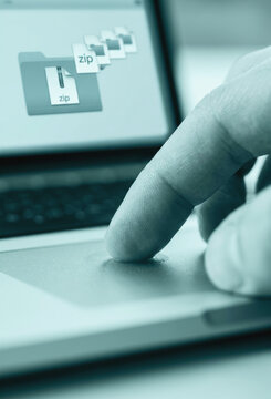 Finger touching a laptop trackpad with zip file icons on screen