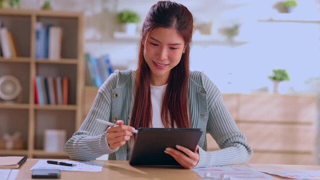 Young woman tablet office smiling desk home workspace asian digital device stylus study creative paperwork bright room bookshelf planning touch screen casual adult