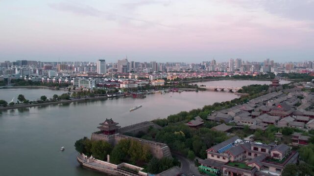 A panoramic view of an ancient waterside city blending traditional architecture with modern urban buildings at dusk.