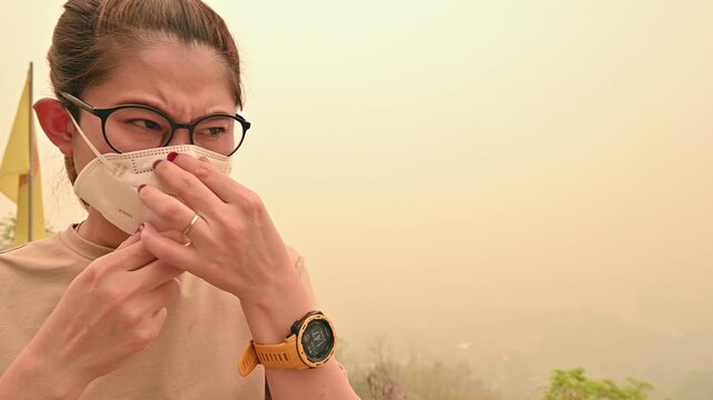 Footage of Asian woman having bad feeling while wearing n95 face mask for prevent bad air pollution. PM2.5 levels meaning the air quality posed a health hazard.
