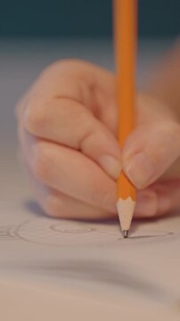 Close up of young person hand drawing circular shapes. Continuous motion shows addition. Soft indoor lighting creates focus solely on steady movement showing hand pencil