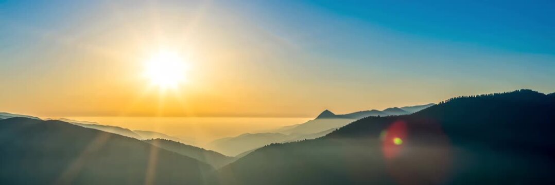 Sunrise over layered mountain peaks and misty valleys, hope concept for travel website banner with copy space
