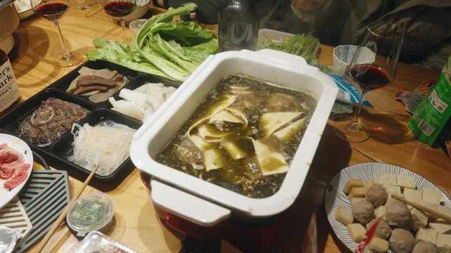 Slow-motion Chinese family hot pot dinner with green peppercorn broth