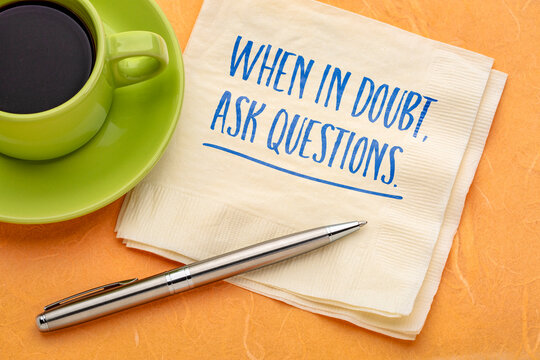 When in Doubt, Ask Questions. Inspirational handwritten message on a napkin with coffee and pen, encouraging curiosity, critical thinking, learning, and better decisions.