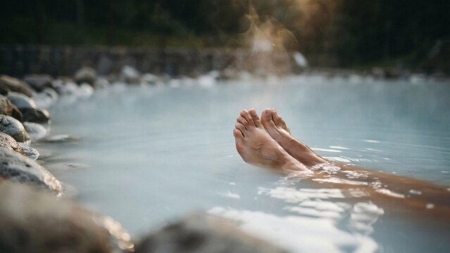 Relaxing feet floating in steaming hot spring water with captures bare feet resting thermal pool surrounded rocks