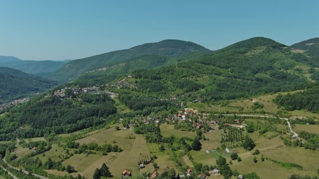 Aerial view of Drvengrad Kustendorf ethno village on Mokra Gora, Serbia, surrounded by green hills and mountains, 4k