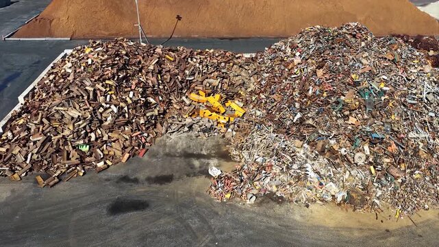 Aerial drone view of a metal recycling plant warehouse showing piles of scrap metal being processed for resource recovery and environmental protection.