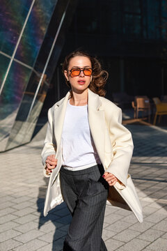Young woman walking toward camera in elegant business outfit. Portrait of female model expressing urban confidence,executive fashion and professional business style.