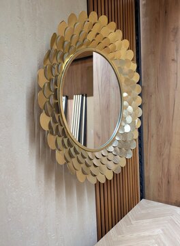 Espejo decorativo redondo con un marco dorado de piezas de metal con forma de p&eacute;talos, instalado en una esquina decorada con listones de madera, 