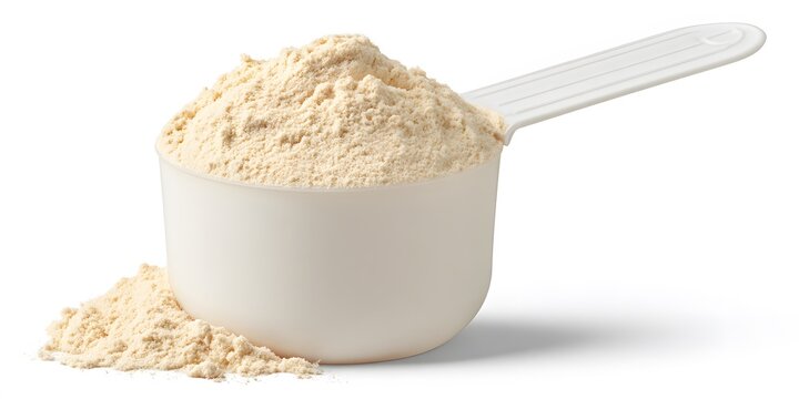White plastic scoop filled with fine beige powder rests on isolated background with small spill beside it.