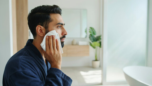 Man wiping face with white cloth in modern bathroom