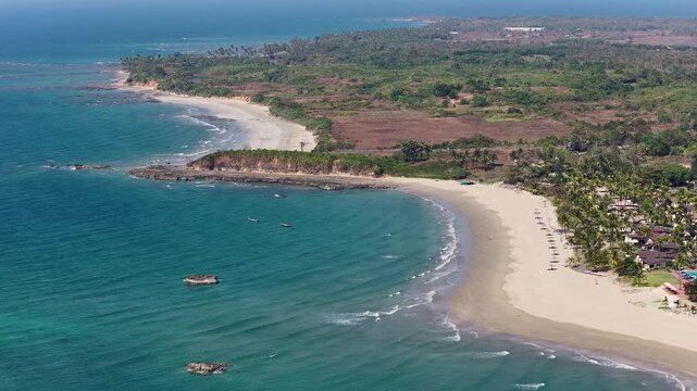 Aerial drone view of golden sand beach, palm trees, hotels and waves and coast of Andaman Sea in Asia. Aerial panorama of coast of famous resort village Ngwe Saung in Myanmar.